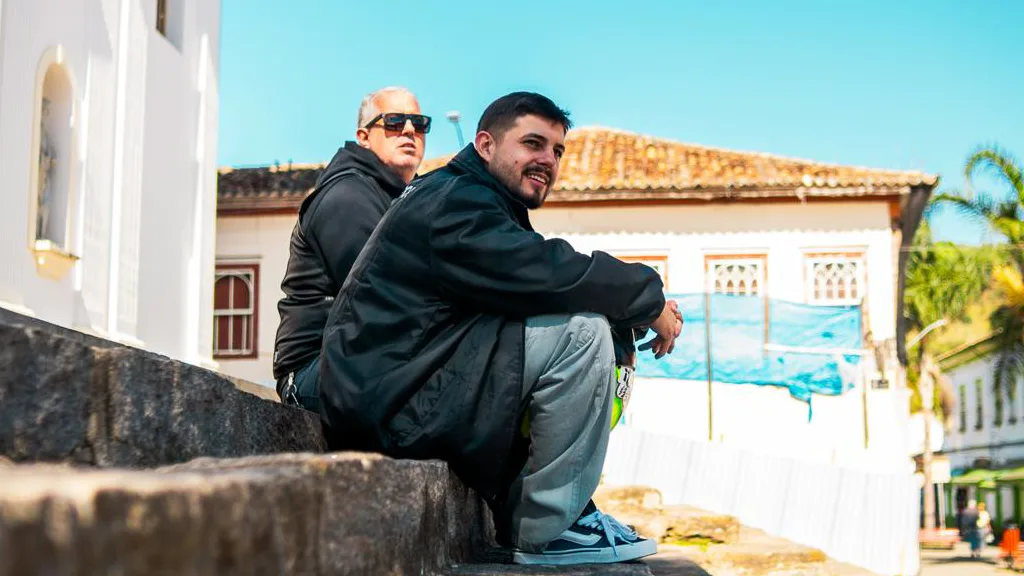 Os consultores de duas rodas da Kikoautos, Dúlio Tunin e Rogério Marcitelli, sentados numa escadaria de pedra numa cidade histórica